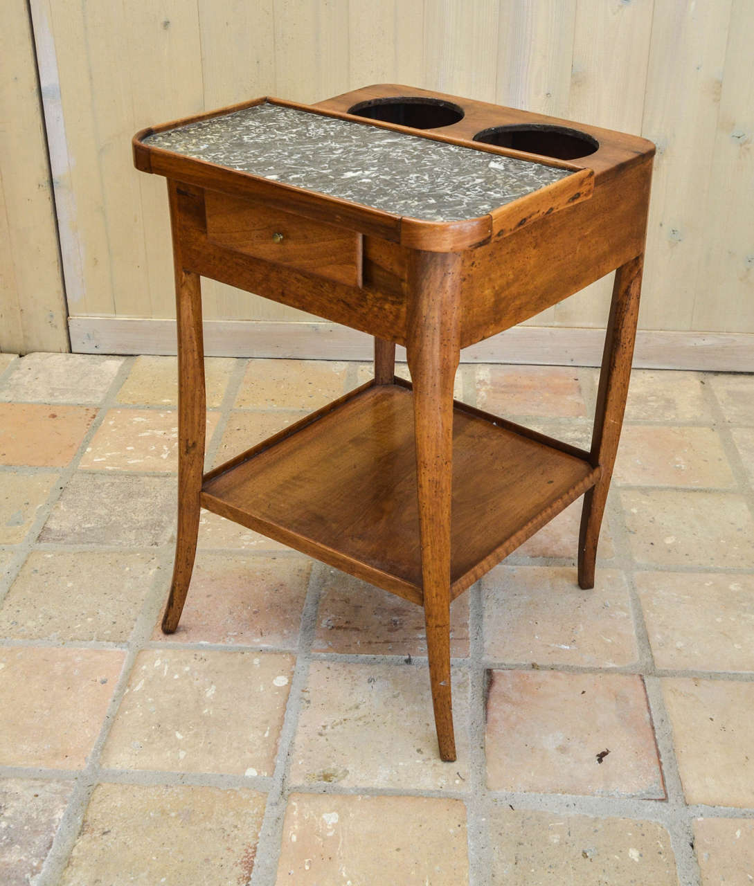 Originally intended for chilling wine or champagne. The square top inset with marble top and two circular wells, over a frieze drawer and platform shelf, on splayed legs. Lacking tin linings.